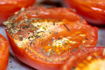 A slice of tomato with herbs on top. The herbs are parsley and basil. The tomato is red and has a green stem