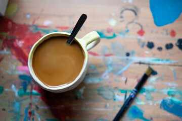 Coffee break on a colorful painter's desk: inspiration and relaxation with copy space