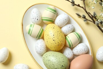 Easter decor concept. Top view photo of colorful eggs in a plate on pastel background