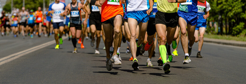 participants run marathon on sunny day long city road