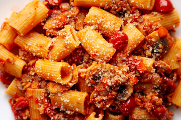 Homemade Italian Sausage and Mushroom Ragu Rigatoni Pasta with Cheese on a Plate, top view. Close-up.