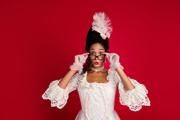 Young woman in elegant white gown poses with surprise on a vivid red background, blending...