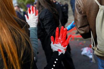 Red painted hands with gloves raised in protest.
