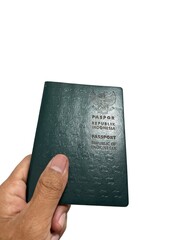A hand holding an Indonesian passport with a green cover, isolated against a white background. Perfect for travel, identity, or documentation concepts
