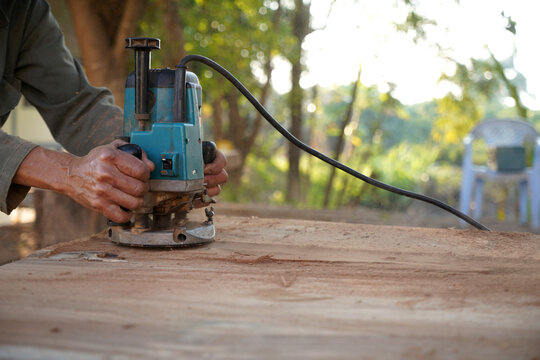 carpenter with hand wood router machine at work.  routing a bevel into plank of pine woodworking construction tool concept furniture