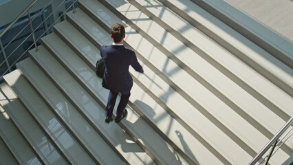 Entrepreneur walking stairs modern building holding briefcase. Confident ceo man