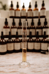 Long transparent glass measuring flask with perfume essential oil, perfumery creation process