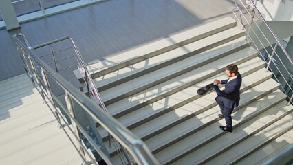 Business manager climbing steps bright office interior. Bearded businessman