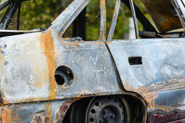 Burned car wreck abandoned on roadside in nature