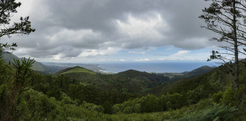 Fototapeta premium Panoramic view of the Asturian coast showing lush vegetation and a stormy sky that gives depth to the scene