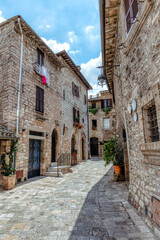 A charming cobblestone street in medieval Assisi, (Umbria, Italy), featuring ancient stone buildings and vibrant flower pots