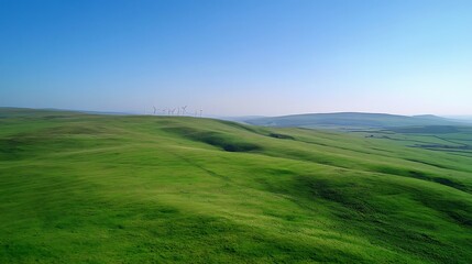 Obraz premium A wind farm on a green hill surrounded by clear blue skies