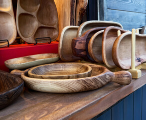 close-up of market stall showcasing variety of wooden kitchenware, including rustic bowls, plates,...