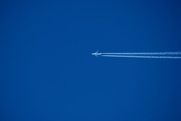 Airplane in the blue sky with trace of a passenger plane.