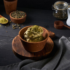 Delicious matcha ice cream is presented in a rustic wooden bowl, surrounded by green tea powder and loose leaves, creating an inviting dessert