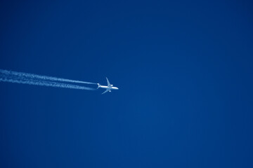 Airplane in the blue sky with trace of a passenger plane.
