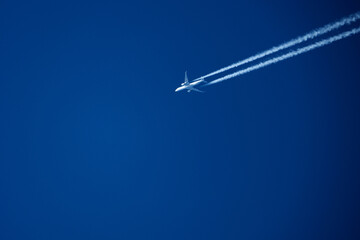 Airplane in the blue sky with trace of a passenger plane.