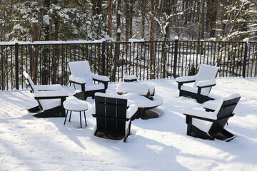chairs around a fire pit covered in snow during winter (back yard backyard bbq burning ring with patio chair) table wintry scene closed for season blizzard