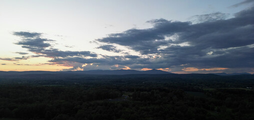 view of catskill mountains at sunset (wide angle aerial mountain vista in catskills hudson valley slide mountain wilderness hiking area) dramatic huge puffy clouds sky cloud formation farm rural area