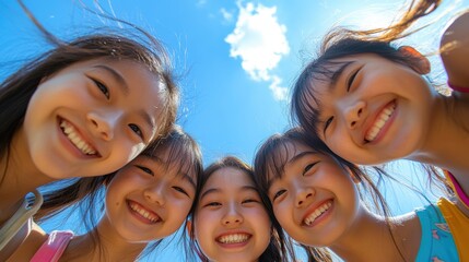 Asian female youngsters looking down at the camera, with the blue sky in the background