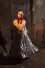 A flowing white vintage dress with lace details and a pearl headdress illuminated by warm light. The scene features a textured aged wall creating a nostalgic, dramatic atmosphere.