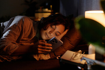 Medium close up relaxed woman lying in comfy bed checking social networks before go to sleep