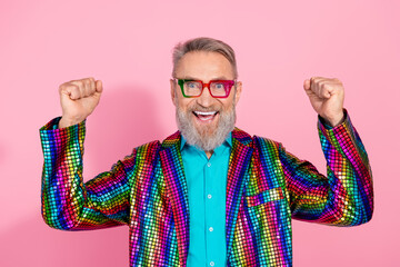 Charismatic elderly man celebrating in flashy outfit on pink background