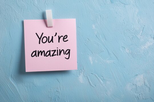 A close-up of a sticky note with a handwritten compliment like "You're amazing" on a desk, symbolizing appreciation