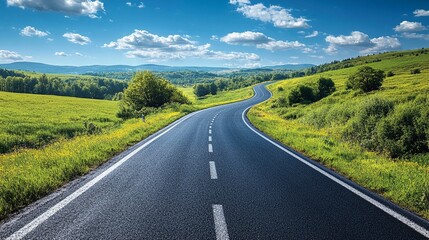 Winding Road Through Lush Green Fields And Trees Under A Blue Sky With White Clouds.