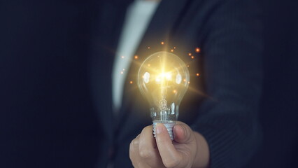 Idea innovation and inspiration concept. Hand of man holding illuminated light bulb, concept creativity with bulbs that shine glitter. Inspiration of ideas for sustainable business development.