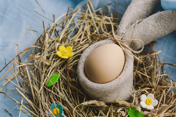 Vibrant Easter eggs are arranged in a cozy nest made of straw, with cheerful flowers contrasting...