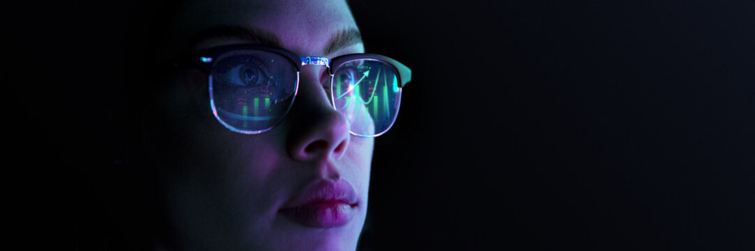 Close-up of focused woman wearing glasses reflecting financial and analytical charts, representing stock market, trading data. Concept of business, modern technologies, finance, investment