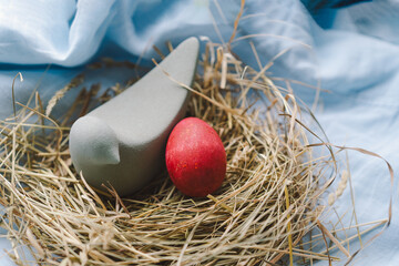 Vibrant Easter eggs are arranged in a cozy nest made of straw, with cheerful flowers contrasting...