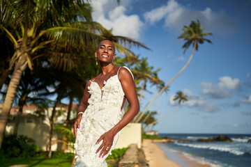 Smiling person, white dress, palm trees, tropical beach. Bridal attire, ocean backdrop, inclusive wedding theme. LGBTQ friendly destination wedding, diversity, sunny coastal getaway.