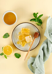 Acacia honey, honeycomb, lemon and mint leaves on beige background. Top view.