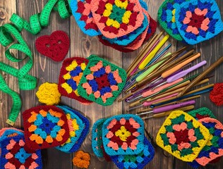 Crochet granny square, clews and hooks on wooden table background photo	
