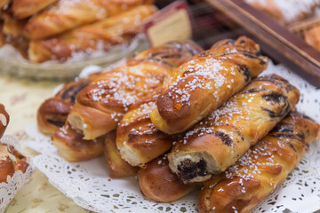 A variety of sweet pastries are beautifully arranged in a local bakery. These treats attract customers with their golden color and sugary toppings, perfect for an afternoon snack.