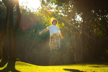 Happy little girl outdoors in nature and has fun jumping with beautiful warm sunset in the park.