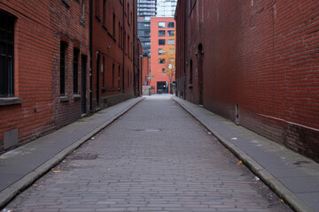 A brick alleyway with a brick building on the right