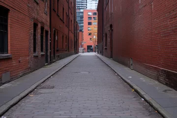 A brick alleyway with a brick building on the right