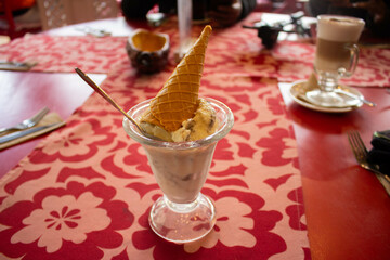helado de vasinilla servido en copa y con cono en el tope