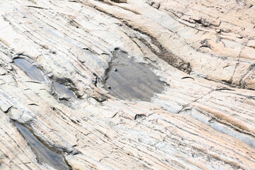 Water has collected on the rock's surface. The rock is a brown color and smooth. In hilly areas, during monsoon season, rain water gets collected in these rocks. Small water pond on top of the rock.