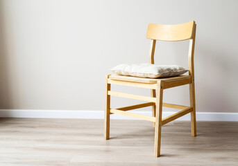 Minimalist wooden chair with cushion in simple room setting