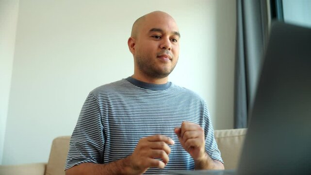 Happy young deaf asian man talking with friend with video call using sign language and showing gestures via internet connection at home, hearing disability and communication showing empathy concept. 
