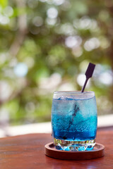 A cold refreshing drink called Cyrstal Blue Ice, a soda drink with blueberry flavor, with a bokeh background. Food and drink photography.