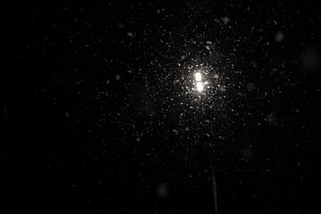 Fototapeta premium Lantern lighting against the backdrop of heavy snowfall at night. Night view of a lantern and snow.