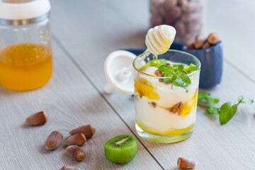 homemade yogurt with kiwi, honey and nuts in a glass on a wooden table