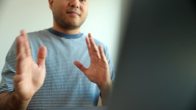 Close up of fingers and hands showing sign language for communication  by video call using laptop at home, a man with hearing disability showing hand gestures to mute impaired people via online.
