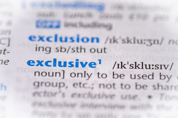 Exclusive word in a dictionary. Selective focus, close up.