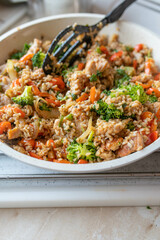 Healthy brown rice pan dish with turkey breast and vegetables in a frying pan